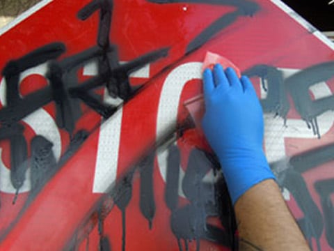 graffiti being wiped away from stop sign