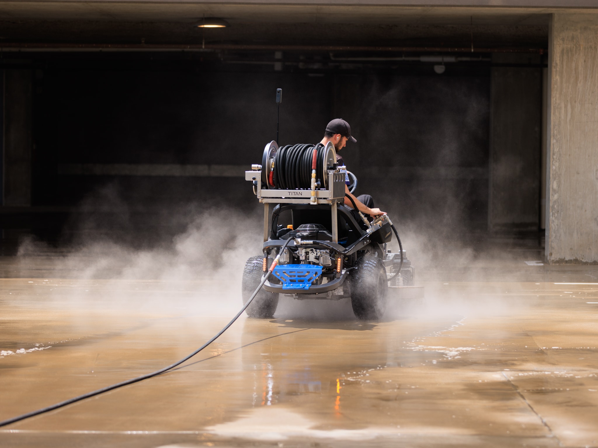 Man operating ride-on surface cleaner with steam coming out of the sides